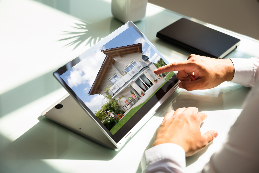 a person pointing at a house on a laptop screen