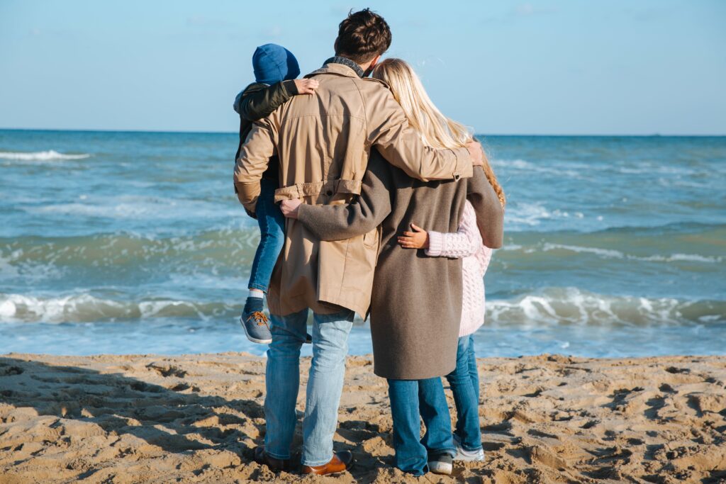 happy-family-hugging-together-on-seashore-in-autum